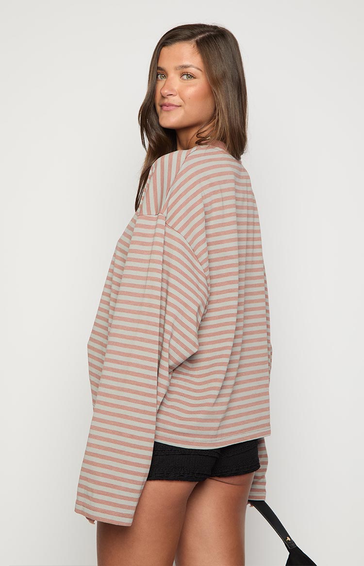 Side view of a muted pastel striped long sleeve top with dropped shoulders and a relaxed fit