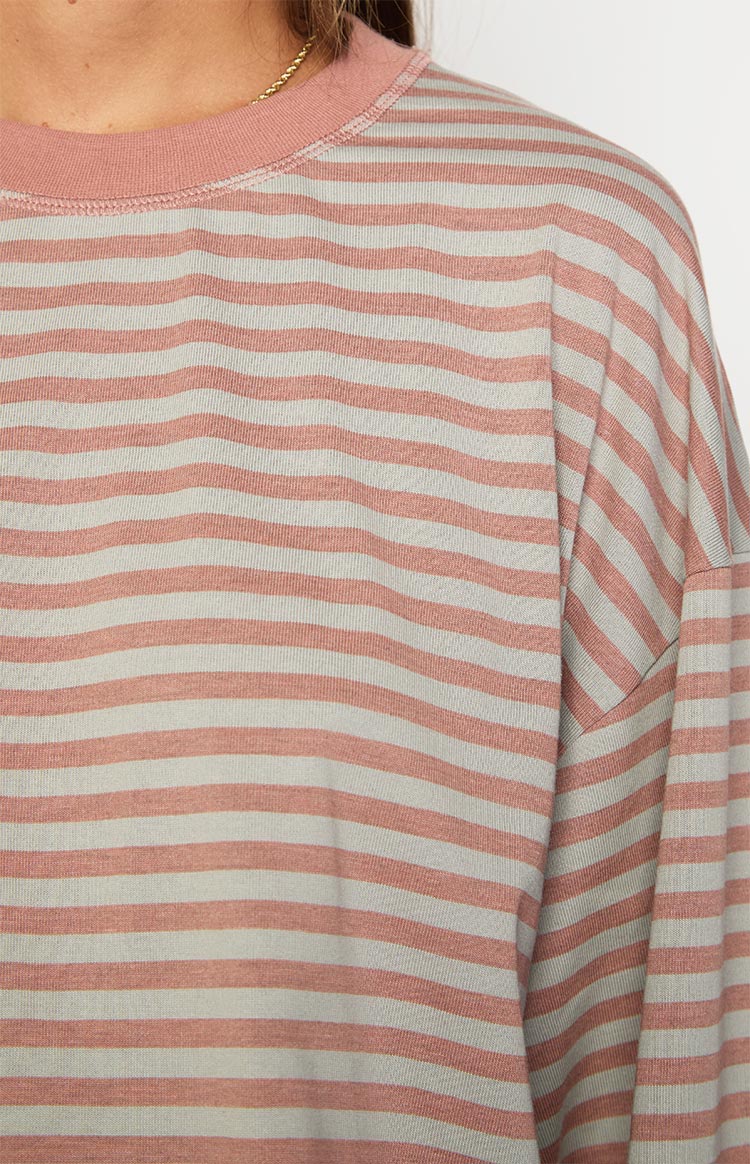Close-up of the ribbed crew neck and dropped shoulder seam on a muted pastel pink and grey striped long sleeve top