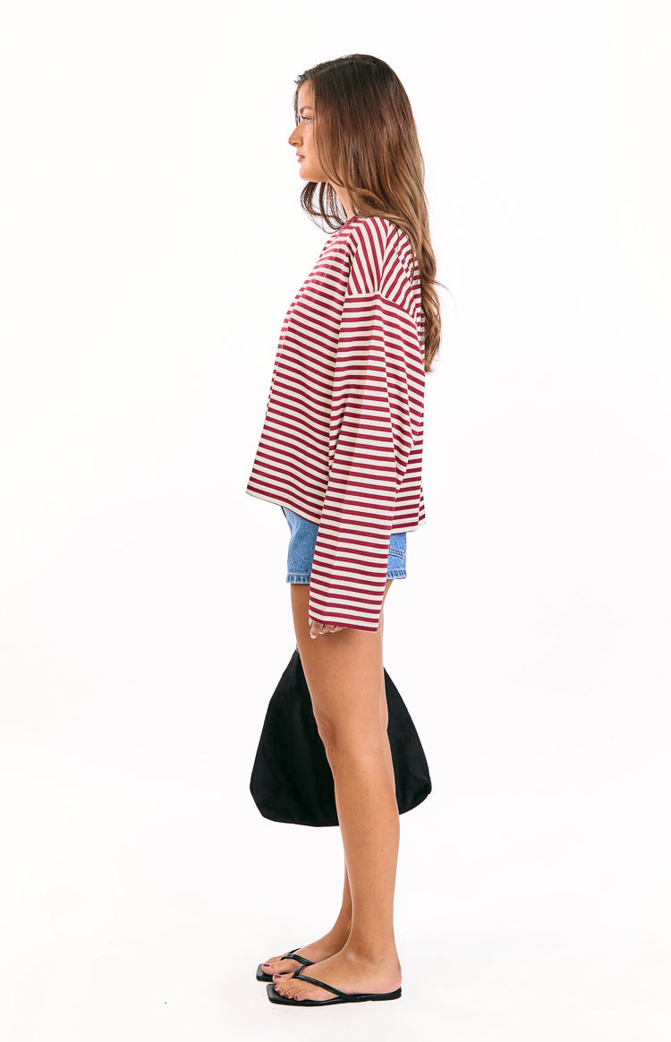 Side view of the wine and white striped long sleeve top with a relaxed, boxy fit and wide long sleeves