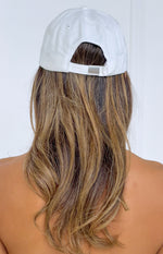 Rear view of a cream baseball cap showing the adjustable strap and silver buckle