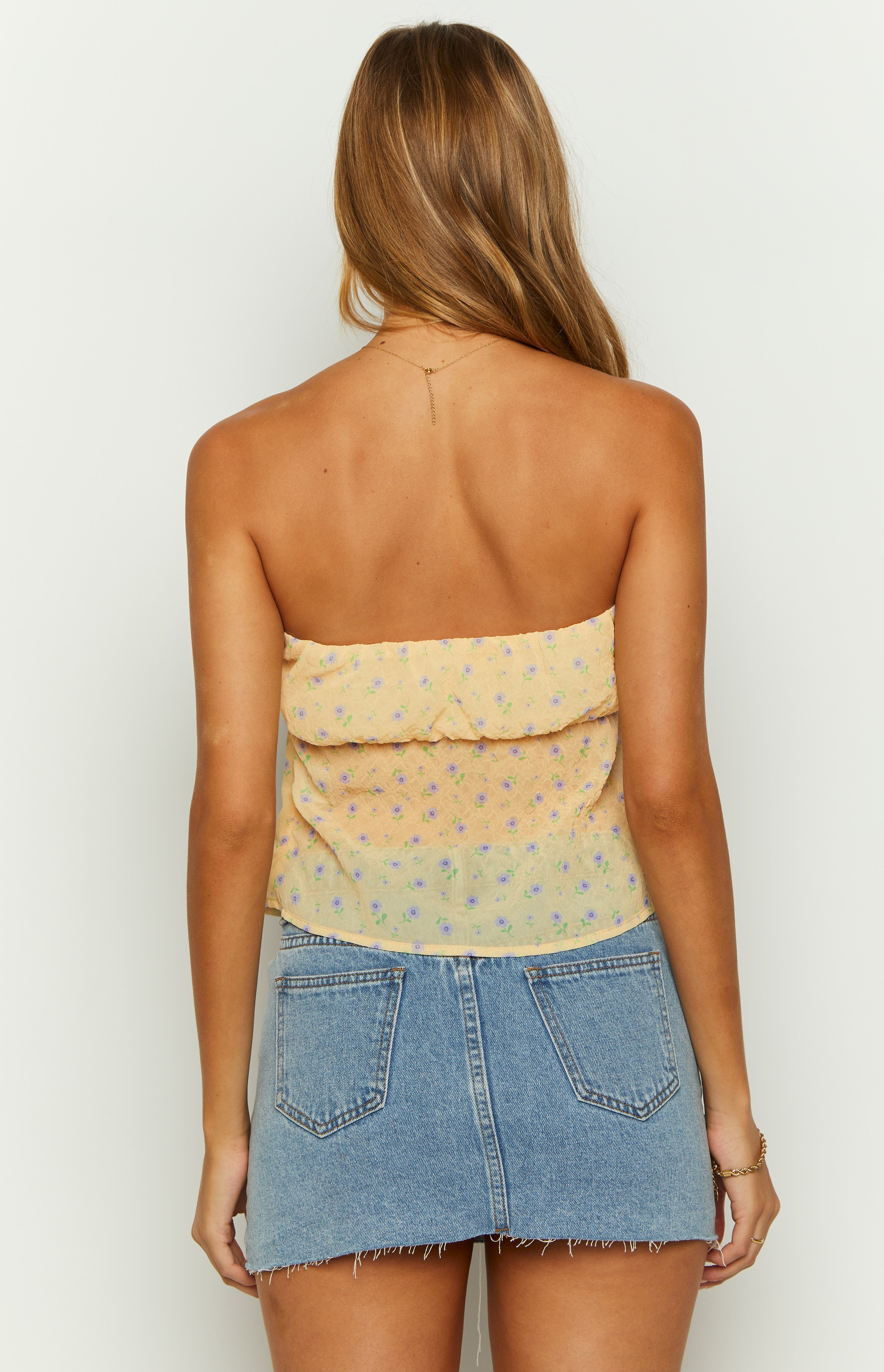 Rear view of the yellow floral strapless top with a gathered ruffled top edge and crinkled texture