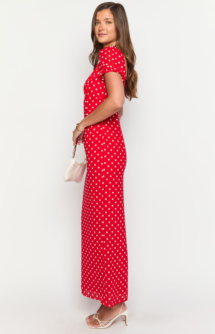 Side view of a red polka dot maxi dress with short puff sleeves and a flowing skirt