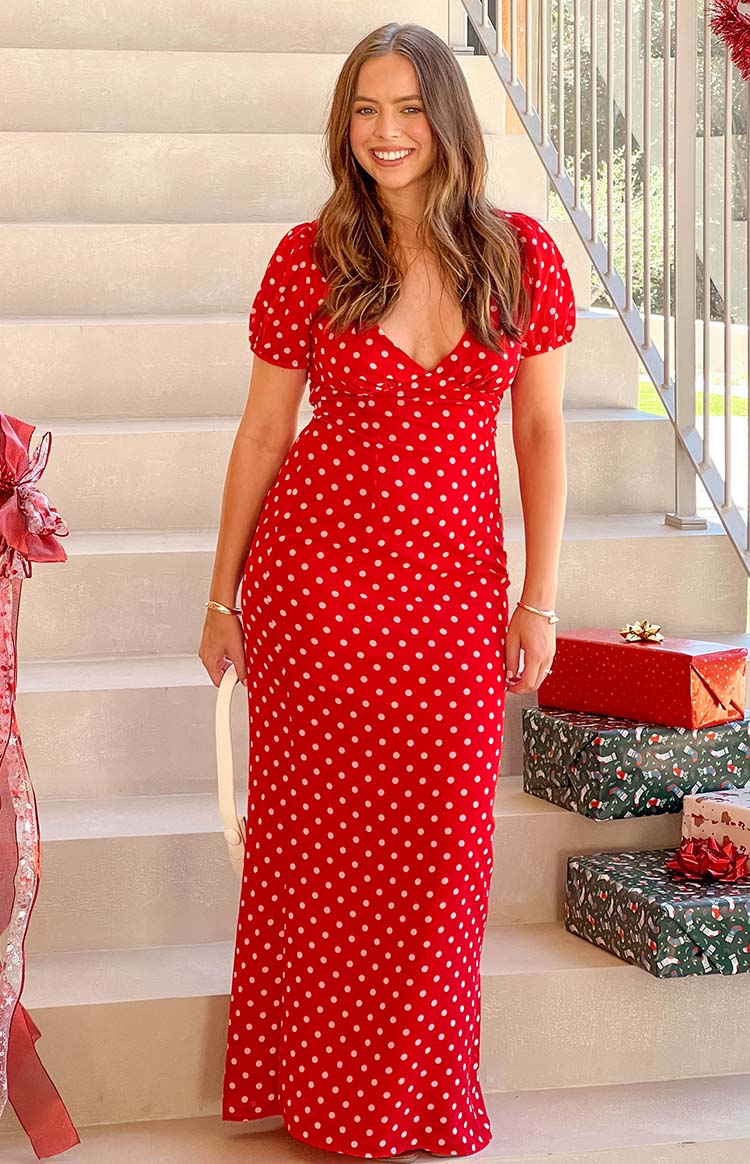 Front view of a red maxi dress with white polka dots, V-neck, short puff sleeves, and ruched bodice