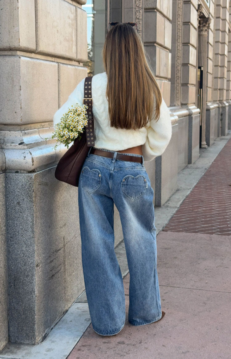 Rear view of mid wash denim slouchy jeans with unique heart-shaped back pockets and a wide-leg fit