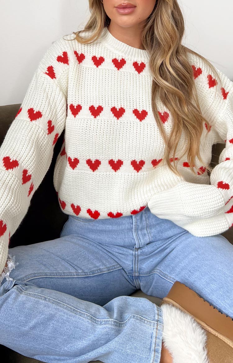 Close-up of the chunky knit white jumper with red heart pattern and ribbed cuffs