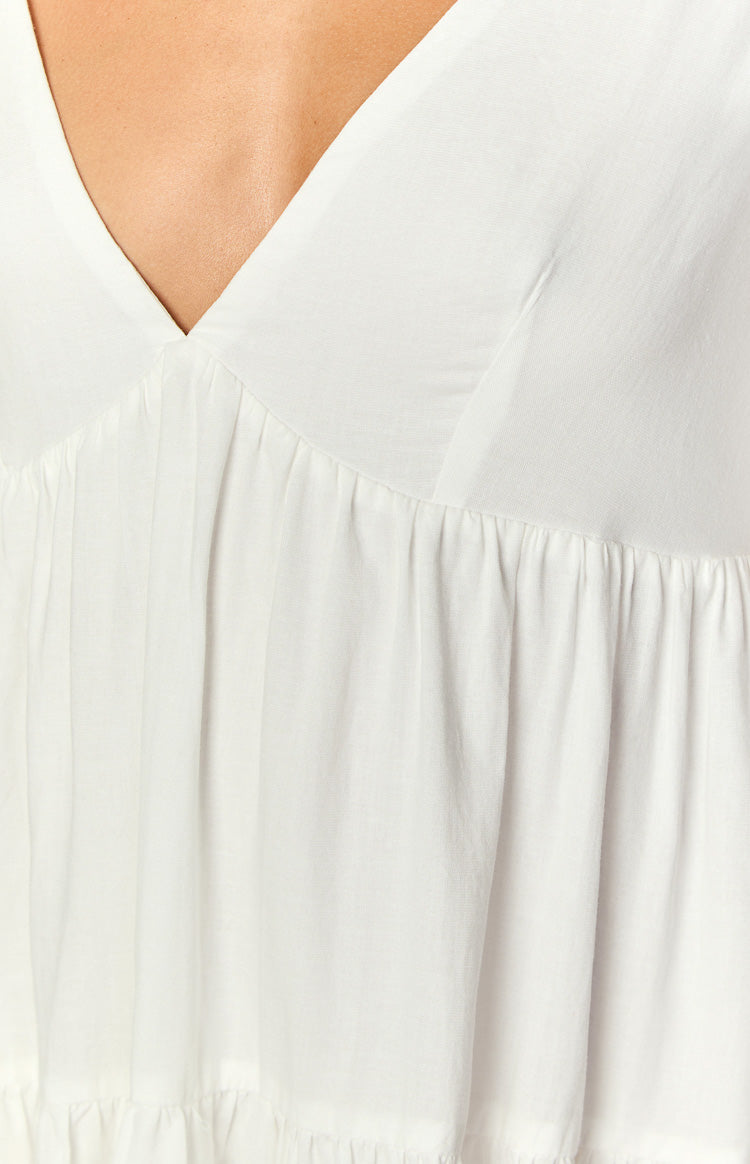 Close-up of the white mini dress V-neckline and gathered bodice with an empire waist seam
