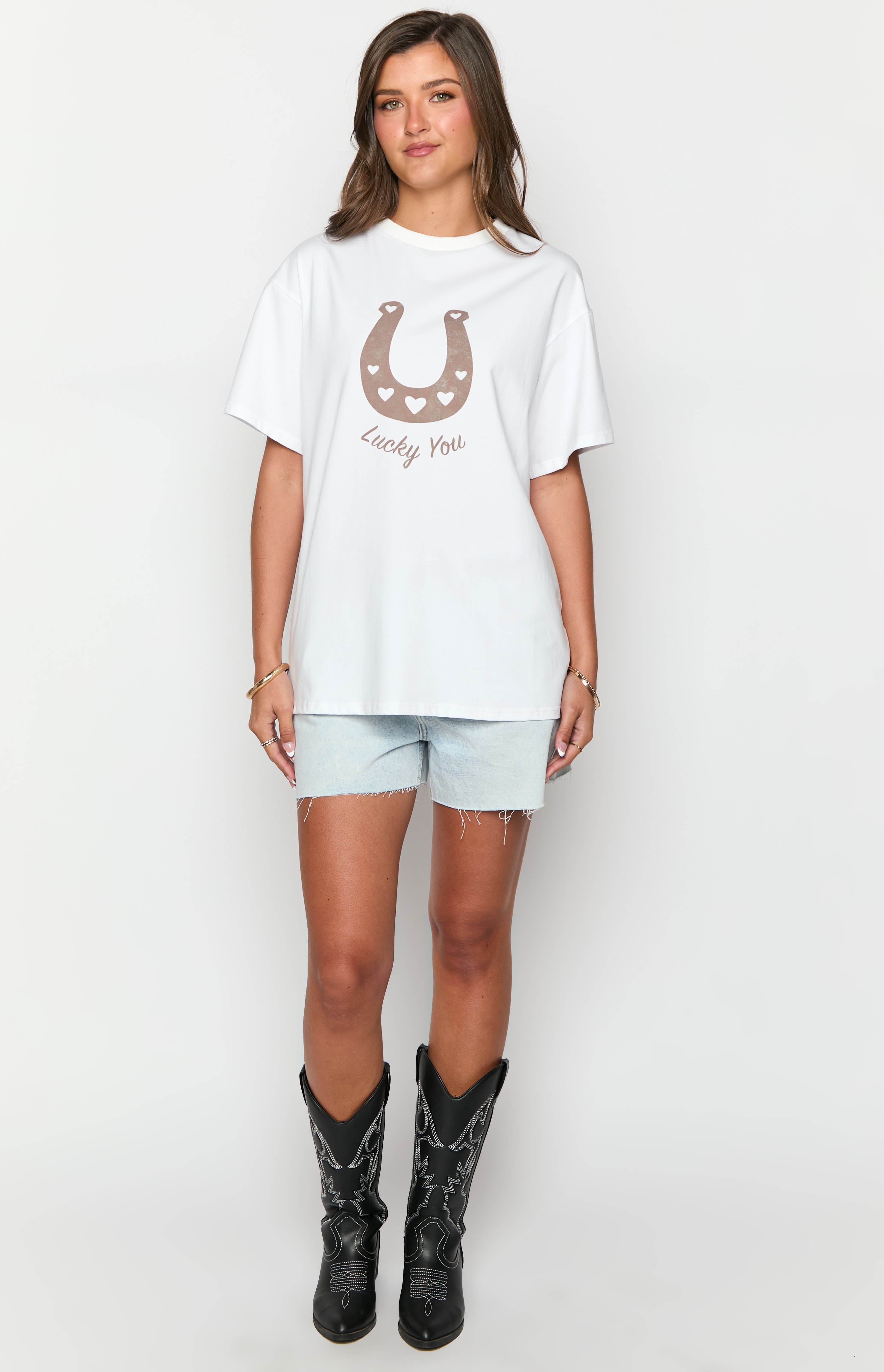 White oversized tee with a brown horseshoe graphic featuring small hearts and Lucky You text