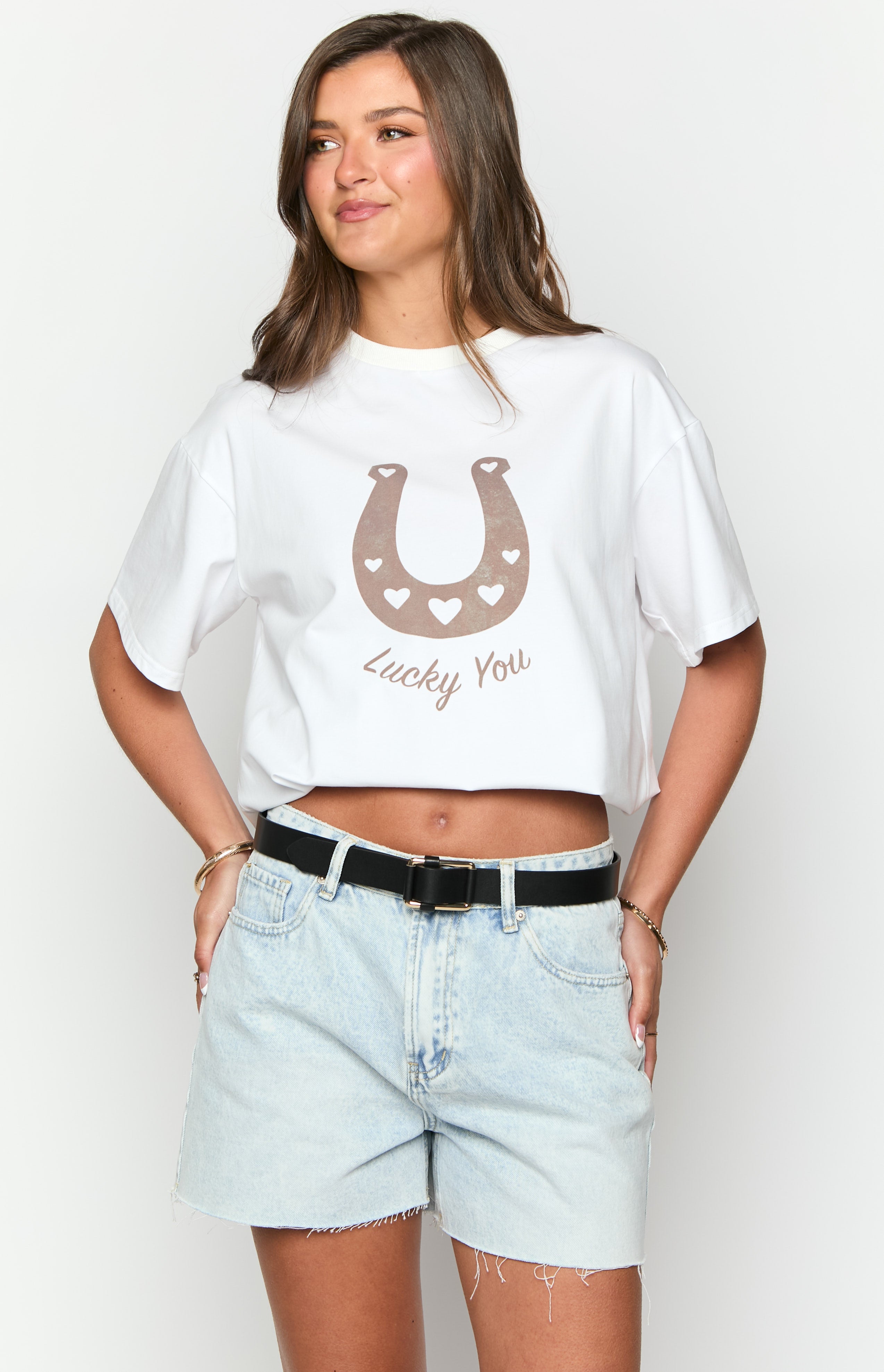 White cropped tee with a brown horseshoe graphic filled with small hearts and 'Lucky You' text