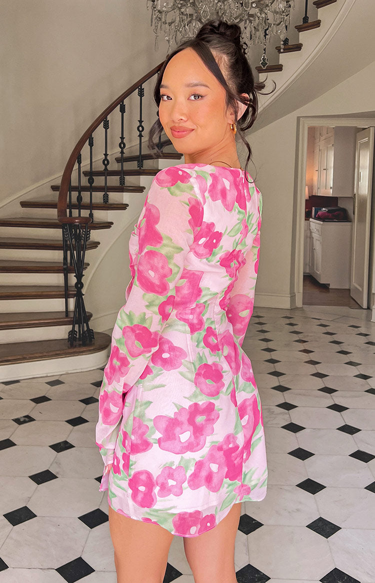 Rear view of the pink floral print mini dress showing the sheer long sleeves and fitted waist