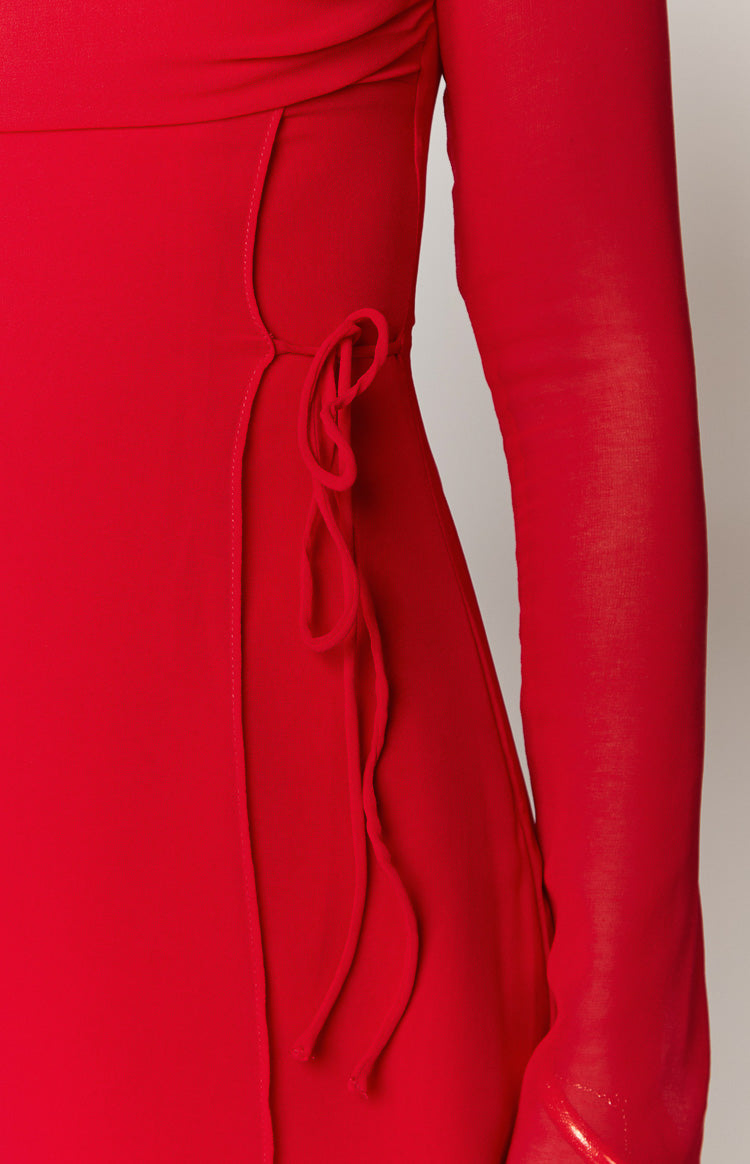 Close-up of the red mini dress showing the side tie detail creating a ruched effect and a long sleeve
