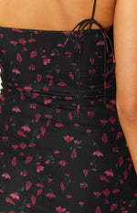 Close-up of the ruched side detail with adjustable tie straps on a black mesh floral print mini dress