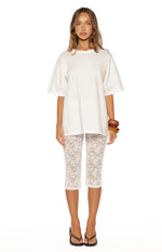 Front view of white floral lace mid-rise capri pants with a fitted silhouette and hem just below the knee