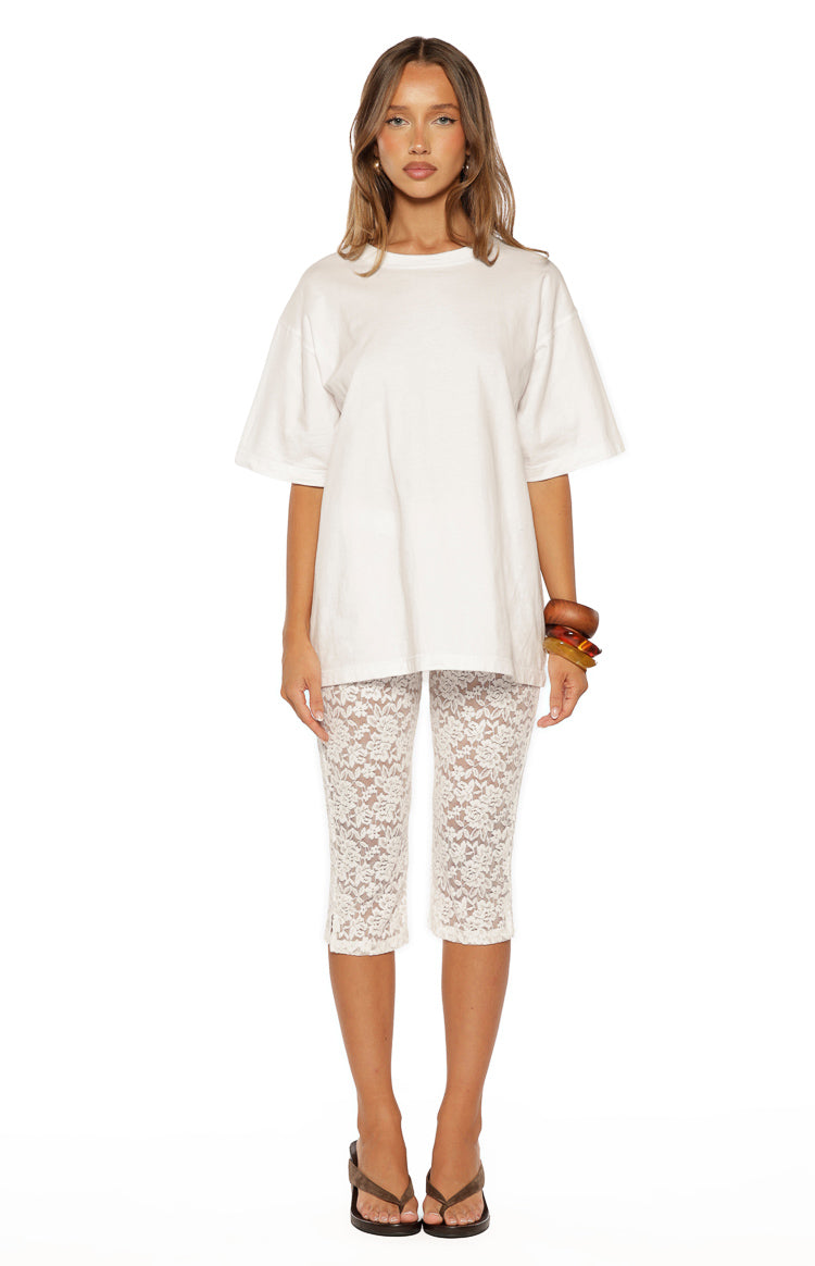 Front view of white floral lace mid-rise capri pants with a fitted silhouette and hem just below the knee