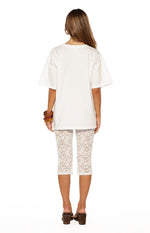 Rear view of white lace mid-rise capri pants with a floral lace pattern and body-hugging fit