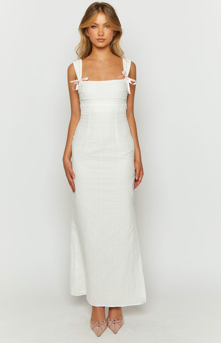 Front view of a white maxi dress with a square neckline, wide straps tied with pink bows, and pintuck details on the bodice
