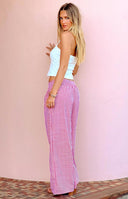 Girl wearing a white halter top and red gingham pants with her hands in her pockets.