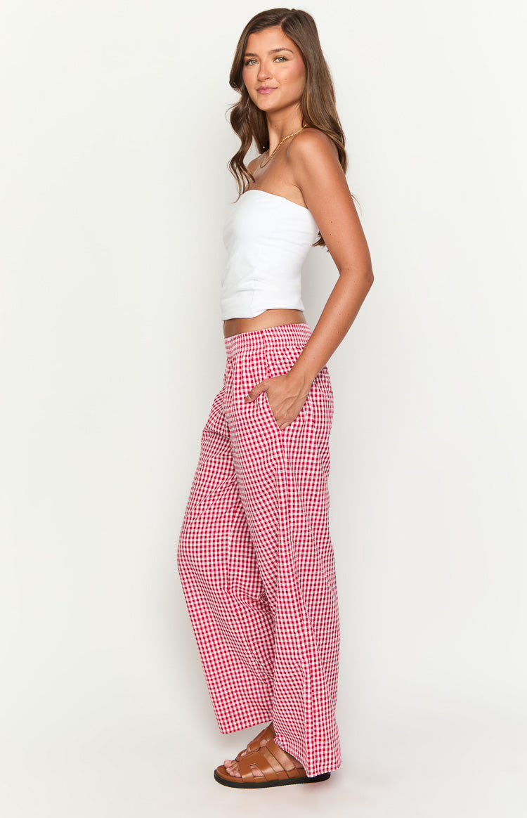 Side view of red and white gingham wide-leg pants with an elasticated waist and side pockets