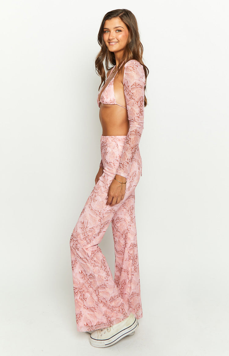 Side view of sheer pink swirl snake print flared pants with a high waist