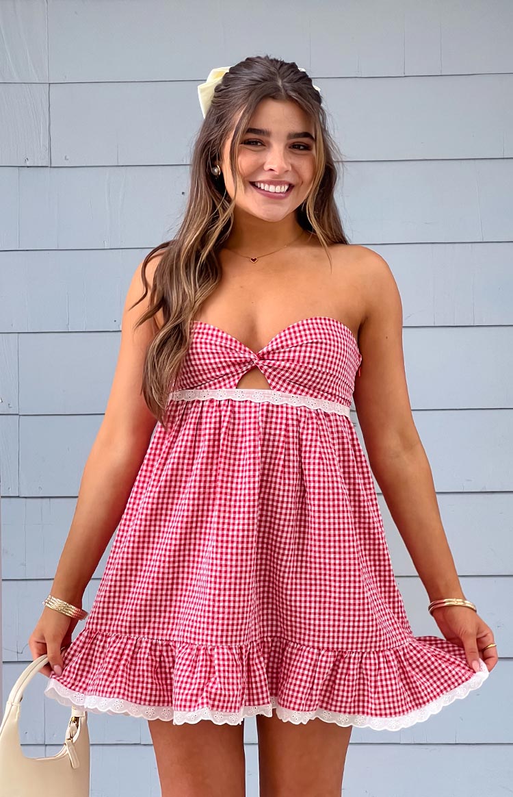 Front view of a red gingham strapless mini dress with a twisted knot bodice and white lace trims