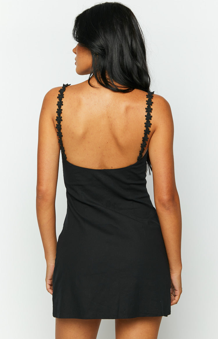 Back of a black mini dress showing the low scoop neckline and delicate floral cutout straps