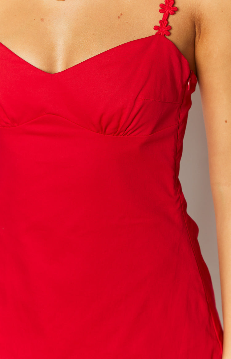 Close-up of the red mini dress showing the ruched bust, floral strap, and side zipper