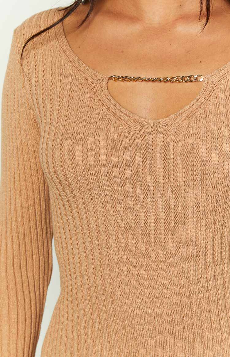Detail shot of the gold chain across the V-neck cutout on a beige ribbed knit jumper