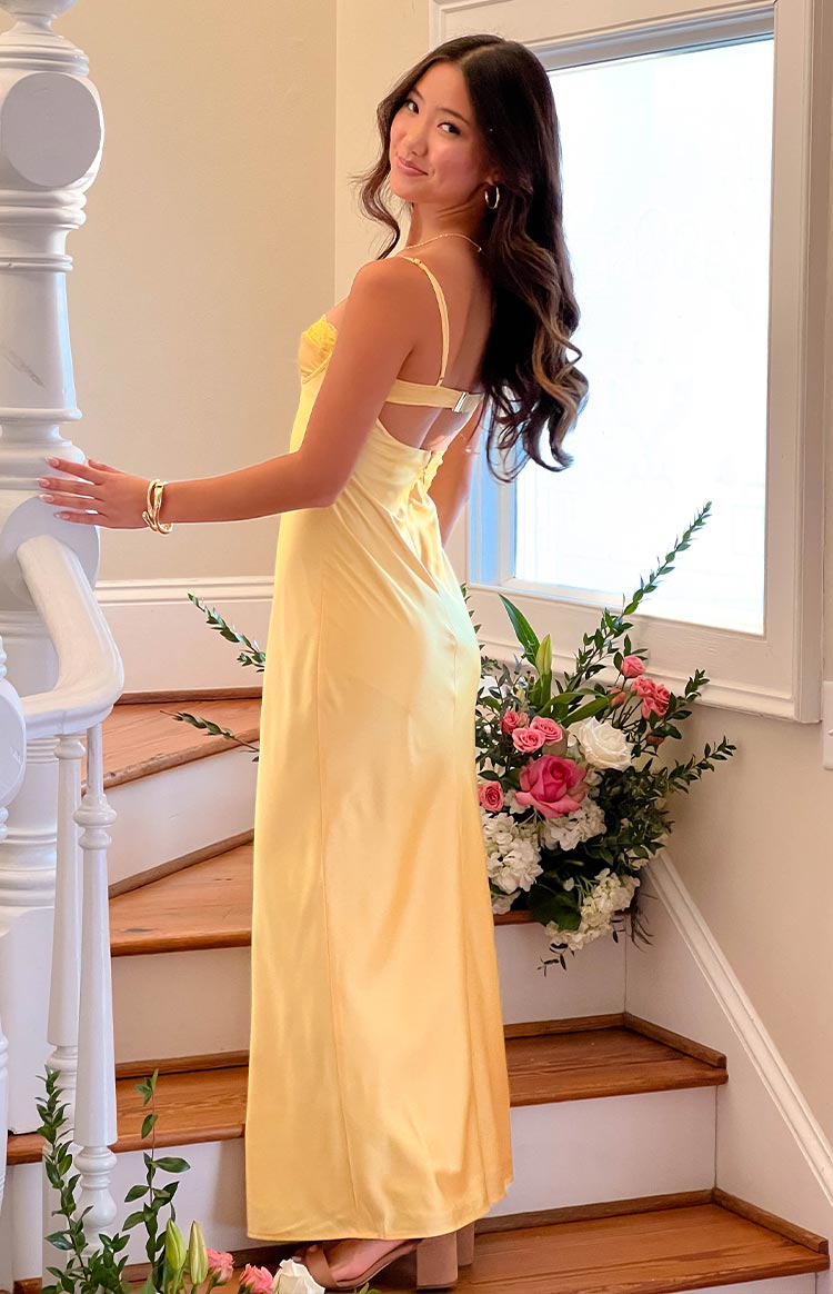 Side and rear view of a yellow lace bust midi dress with spaghetti straps, a back cutout, and metal clasp