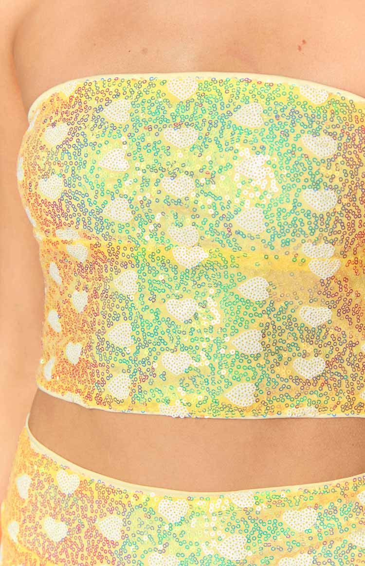 Close-up of the iridescent yellow sequin fabric with white heart patterns on the strapless corset top