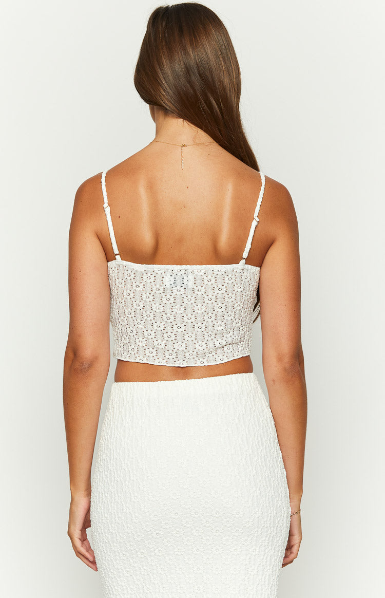 Rear view of a white crop top with thin adjustable spaghetti straps and a textured broderie fabric