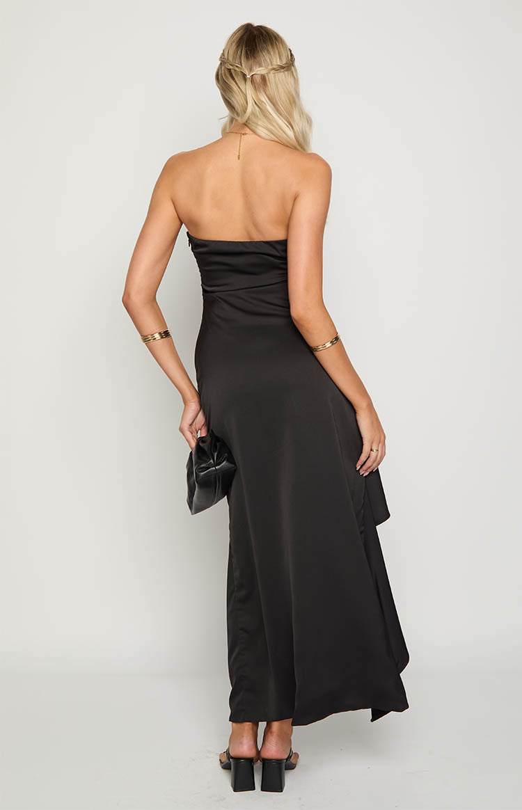 Rear view of a black strapless maxi dress with a fitted bodice and a draped, asymmetrical hemline