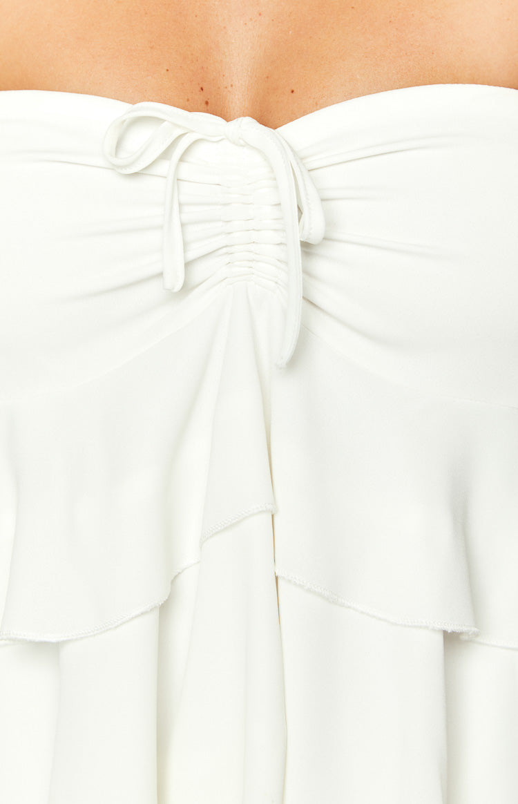 Close-up of the white strapless mini dress's ruched drawstring detail at the bust and tiered ruffles