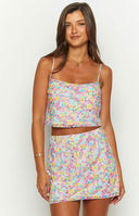 Close-up of the fitted mini skirt showing the vibrant painted floral print in pink, yellow, blue, and green