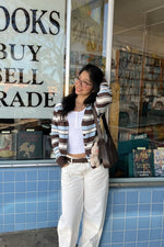 Front view of a brown, light blue, and white striped button-down cardigan worn open, showing its relaxed fit