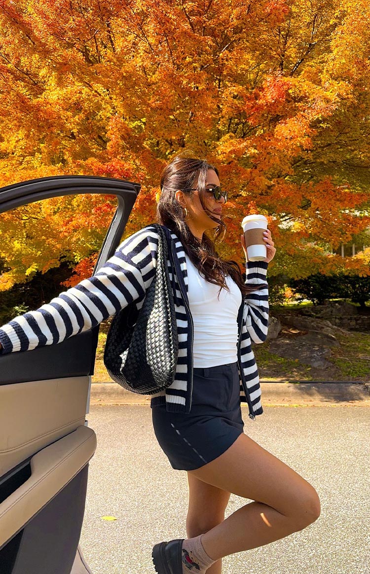 Side view of a navy and white striped knit zip sweater, worn open, showing the full-length zipper and ribbed cuffs
