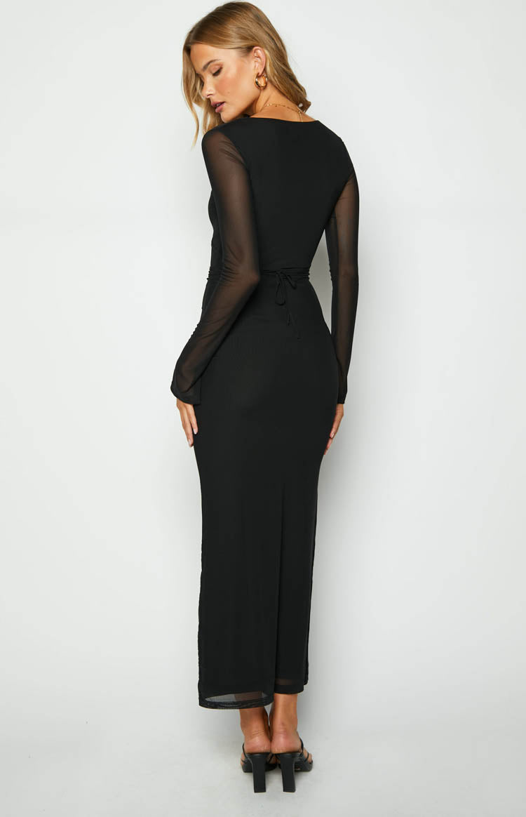 Rear view of a black maxi dress with sheer mesh long sleeves, a tie-back waist, and a fitted skirt with a back vent