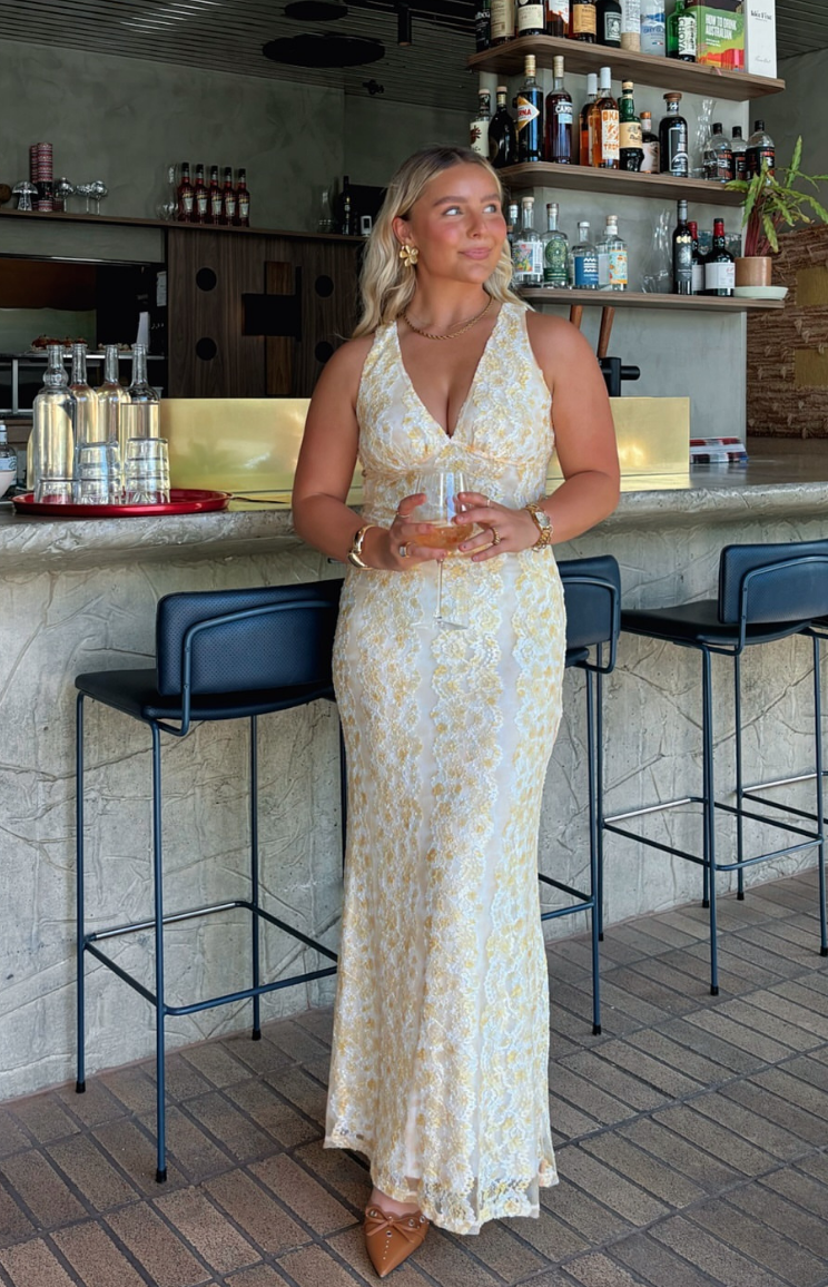 Full length view of a yellow lace maxi dress with a deep V-neck halter neckline and a fitted silhouette