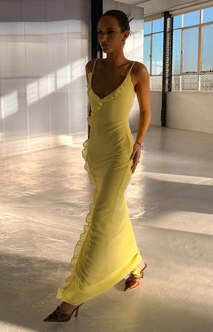 Side view of a yellow maxi dress with ruffles along the V-neckline and down the side seam