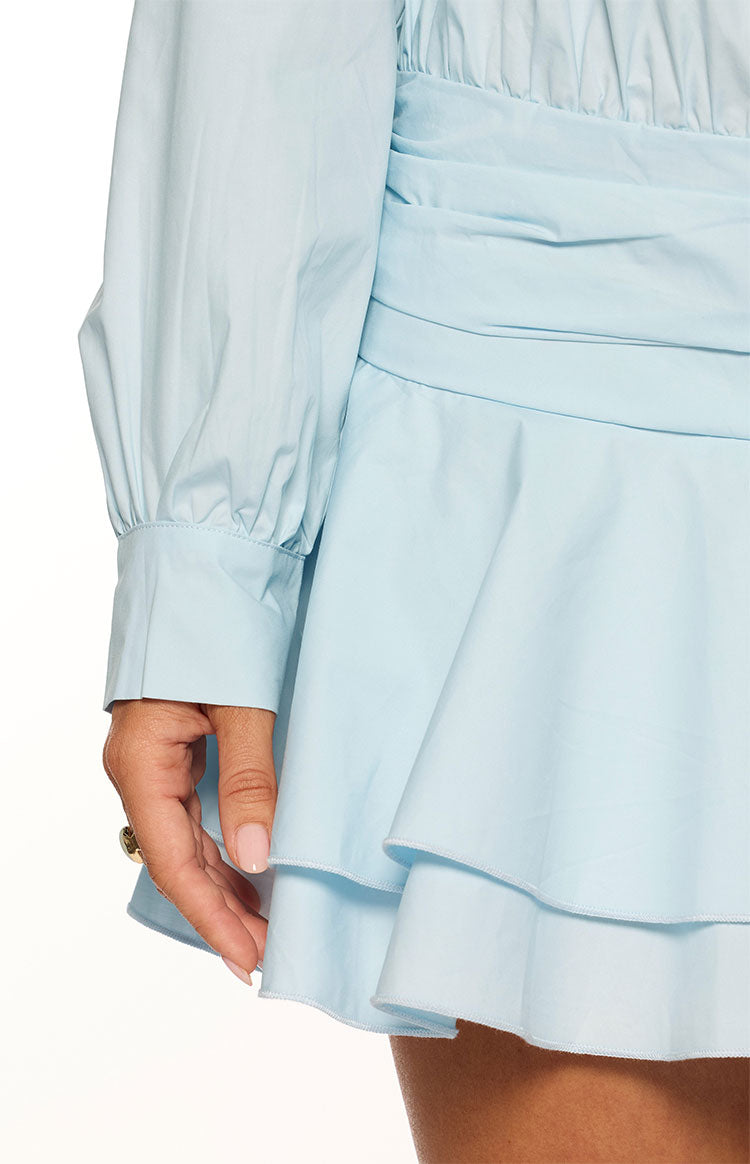 Close-up of the light blue long sleeve with buttoned cuff, ruched waist, and tiered ruffle mini skirt
