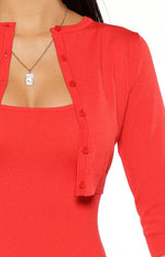 Close-up showing the red knit cardigan with button-front and 3/4 sleeves layered over a square neck dress