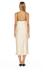 Rear view of a cream satin midi dress with thin black adjustable spaghetti straps and black trim
