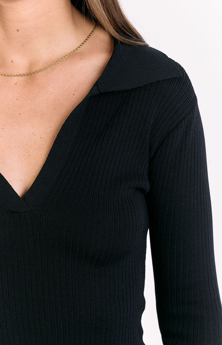 Close-up of the black ribbed knit texture on the shoulder and collared V-neckline of the sweater