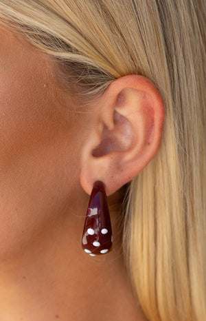 A girl wears the Norah Burgundy Polka Dot Hoops showing the scale and style of these chunky statement earrings a fun party accessory.