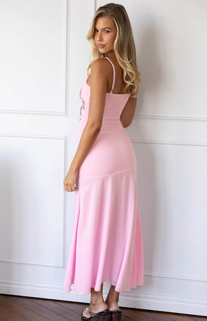 Side profile of a light pink midi dress with thin straps, floral embroidery, and a flowing flared skirt