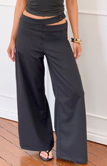 Black wide-leg pants with an asymmetric waist cutout and two button closure on the left hip