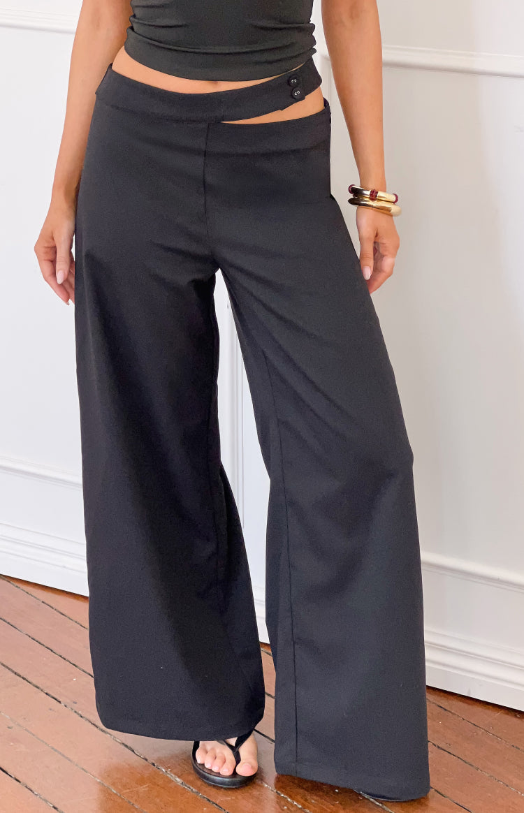 Black wide-leg pants with an asymmetric waist cutout and two button closure on the left hip