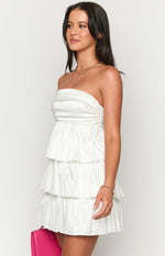 Side view of a white strapless mini dress with a ruched bodice and tiered pleated skirt