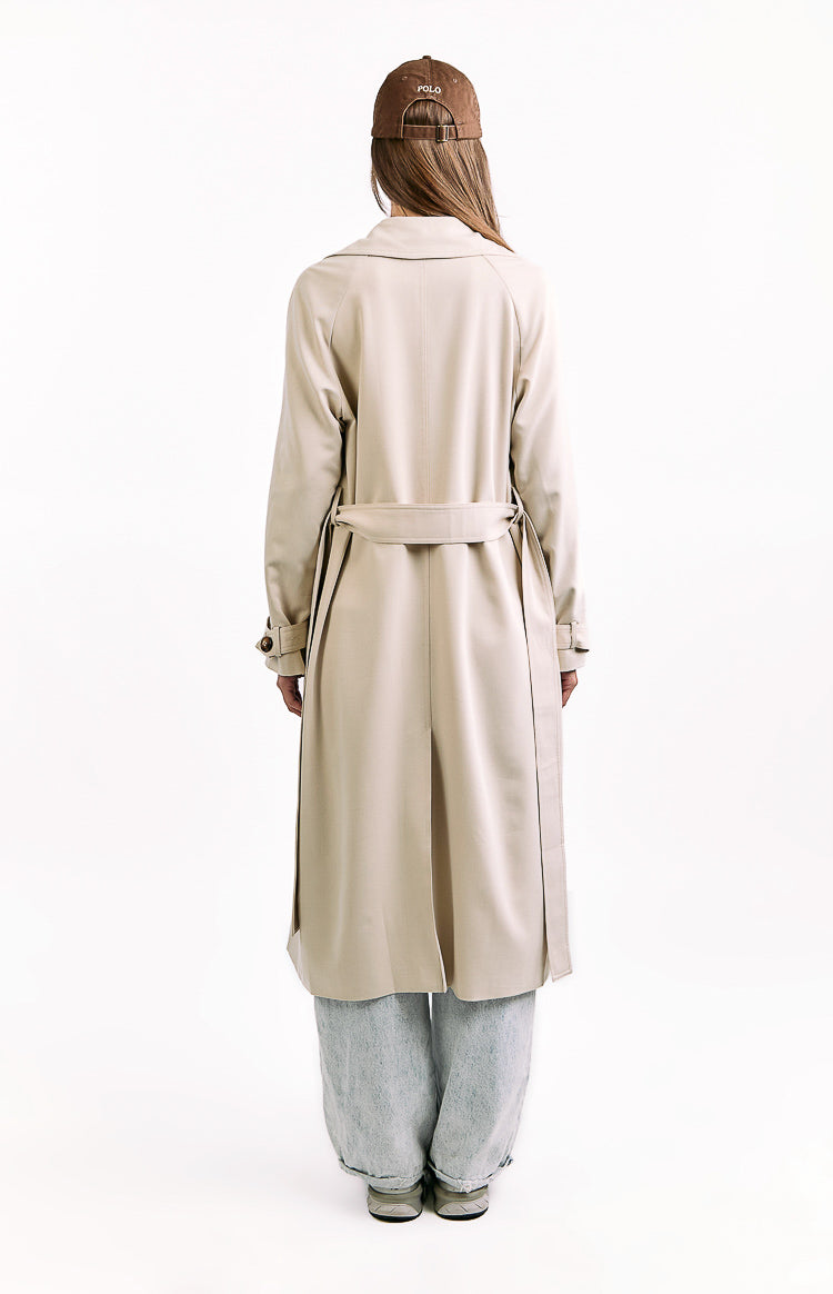 Back view of a cream longline trench coat showing the tied waist belt, raglan sleeves, and a central back vent
