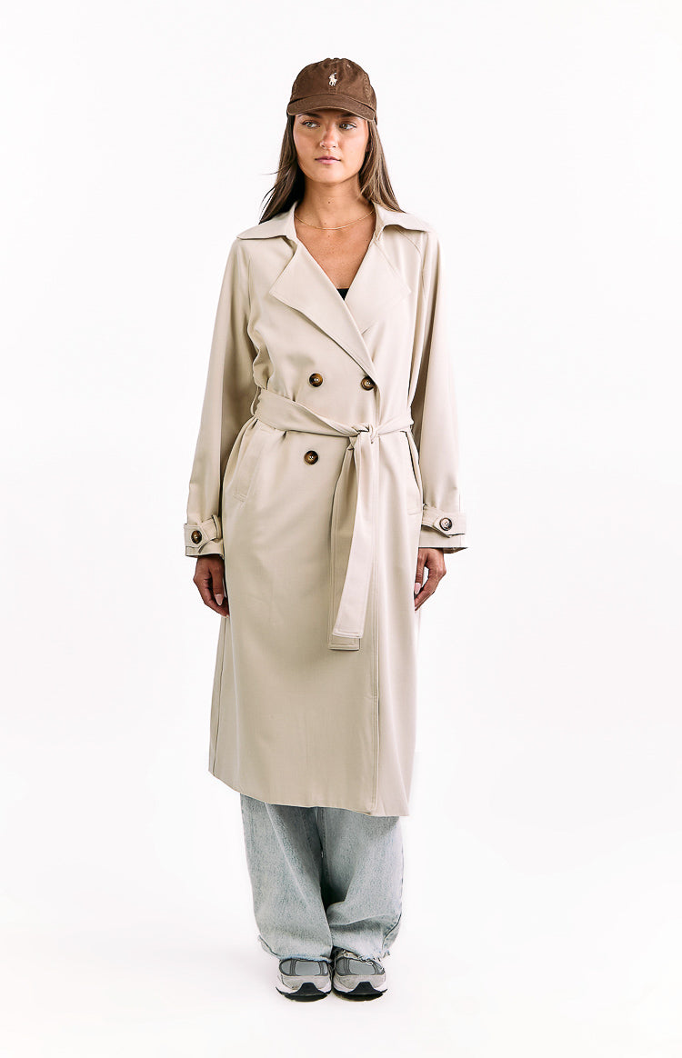 Front view of a cream double-breasted trench coat with a tied waist belt and buttoned cuffs
