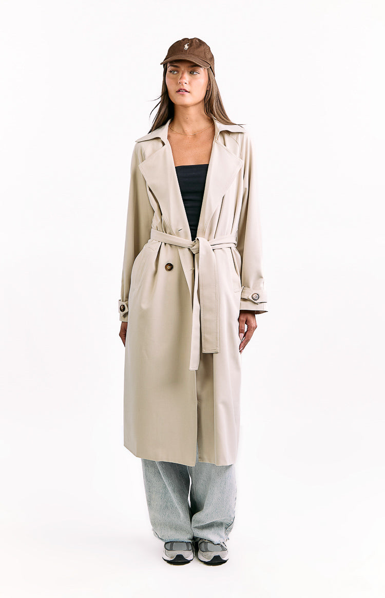 Front view of a cream longline trench coat with wide lapels and a tied waist belt