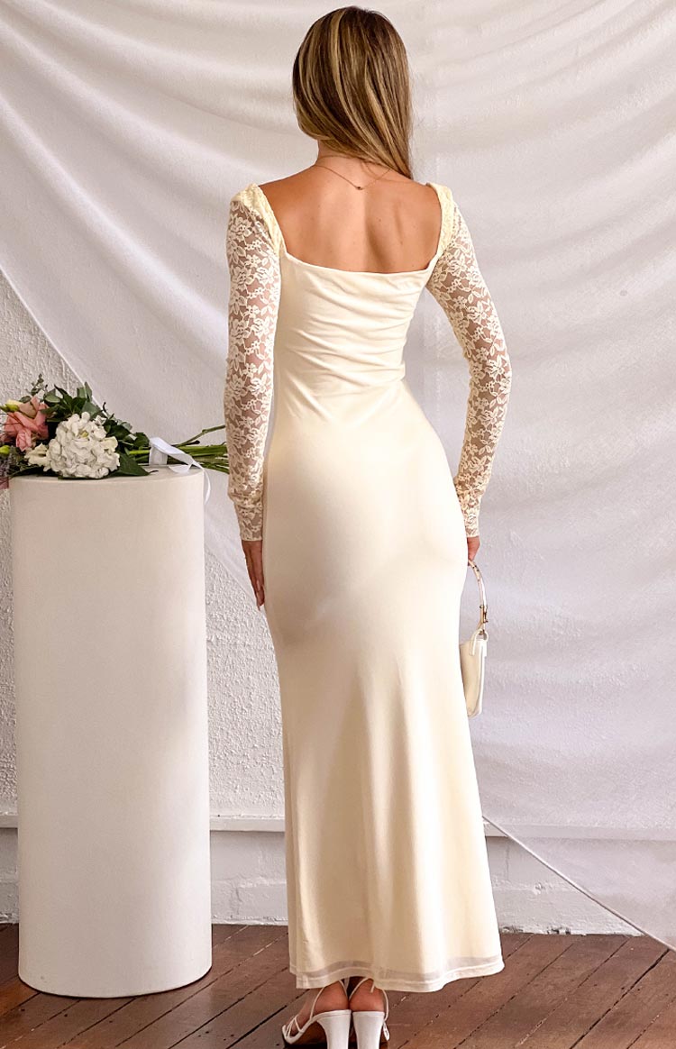 Back view of a cream maxi dress showing the square neckline, fitted bodice, long lace sleeves, and sheer hem